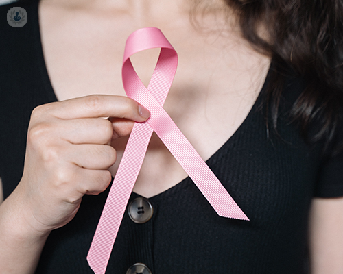 A young woman holding a pink breast cancer ribbon