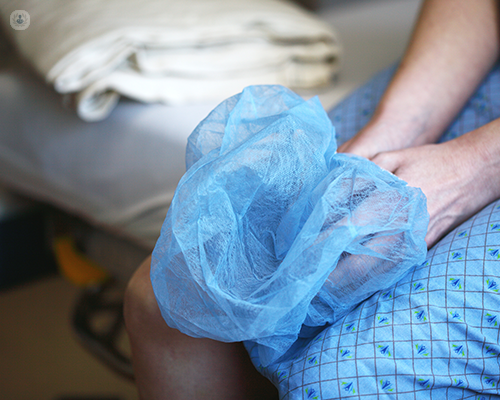A hospital patient resting their hands on their lap while holding a surgical hair cap. 