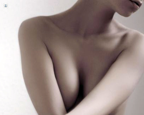 The torso of a woman's body with breasts partially covered by her arms
